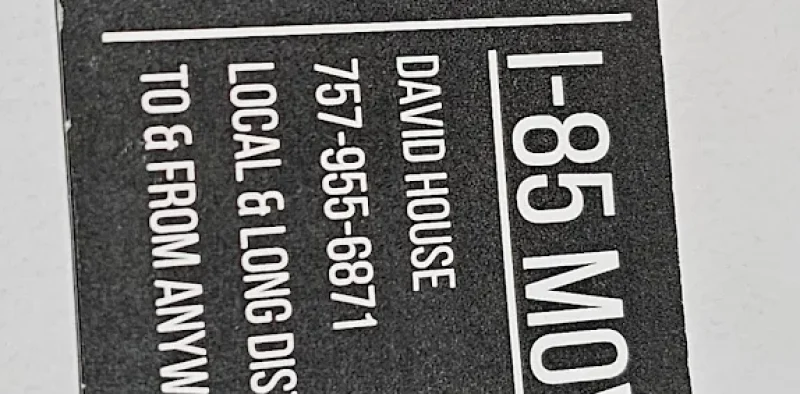 Black business card for I-85 Movers with white text and an Interstate 85 shield logo. Text reads: I-85 MOVERS DAVID HOUSE 757-955-6871 LOCAL & LONG DISTANCE MOVING TO & FROM ANYWHERE IN THE USA